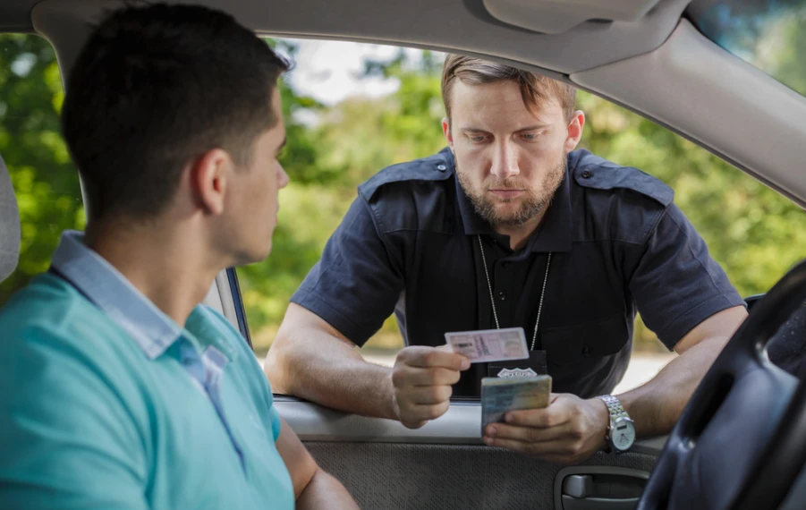 odič drží v ruke vodičský preukaz a malý technický preukaz počas cestnej kontroly