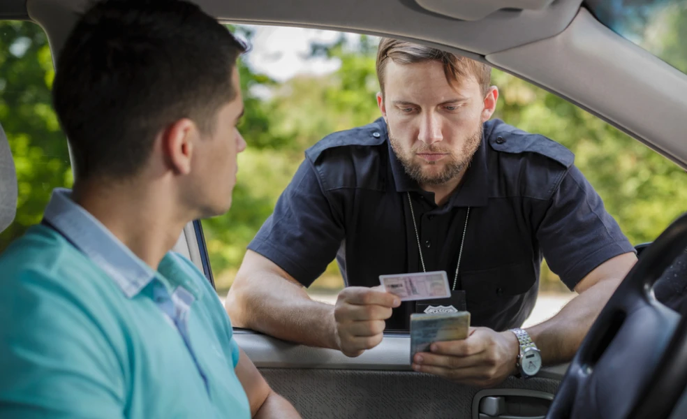odič drží v ruke vodičský preukaz a malý technický preukaz počas cestnej kontroly
